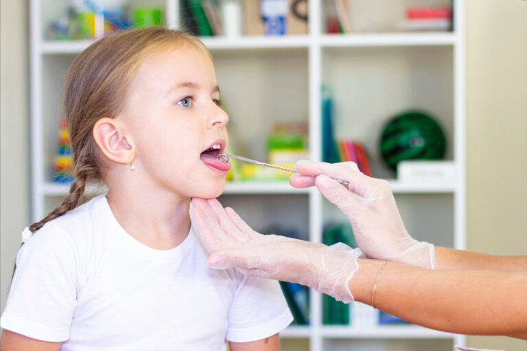 Speech therapy massage of the girl's tongue. a speech therapist makes a tongue massage to a child with a staging probe